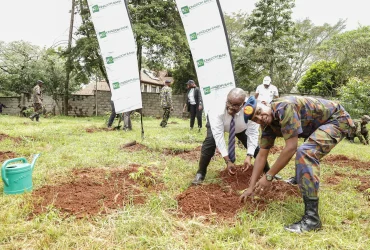 Kingdom Bank employee planting a tree with a Kenya Army Soilder.